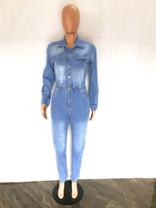 Detail view of denim jumpsuit featuring front buttons, chest pockets and washed blue texture