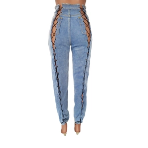 Détail d'un jean bleu clair à taille haute avec lacets latéraux et oillets métalliques