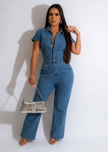 Detailed macro of the blue denim jumpsuit showing metal buttons and large patch pockets
