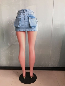 Close-up of light blue denim mini skirt featuring large flap pockets and raw hem details