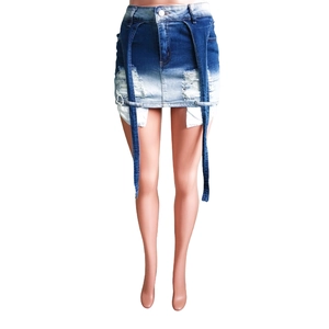 Détail de mini-jupe en jean dégradé avec des trous déchirés et de longs rubans décoratifs