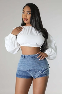 Detail of blue washed denim shorts featuring a unique asymmetric crossover waist design
