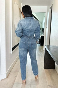 Rear view of a light blue washed denim jumpsuit featuring elastic waist and large back pockets