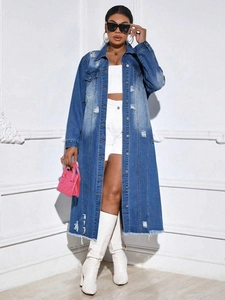 Detail of ripped long denim trench coat with frayed edges and distressed wash finish