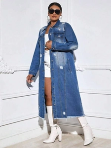 Detail of distressed denim coat with ripped effects and raw hem fringe on washed blue fabric
