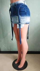 Détail d'une mini-jupe en jean dégradé avec déchirures et longues lanières décoratives