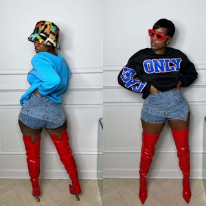 Detail of high-waisted denim shorts styled with bright red patent leather over-knee boots