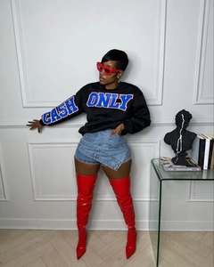 Fashionable denim skort paired with red high boots and a black graphic sweatshirt
