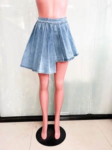 Dettaglio della gonna a pieghe in denim celeste con un esclusivo design dell'orlo asimmetrico
