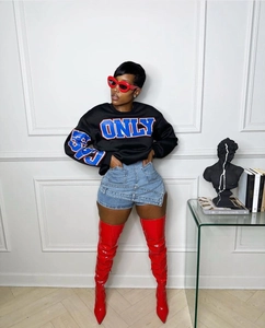 Close-up of light blue distressed denim skort paired with bold red patent leather boots