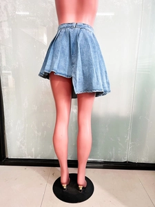 Dettaglio gonna a pieghe asimmetrica in denim azzurro con zip sulla parte posteriore