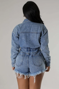 Rear view detail of high waist denim shorts with frayed edges and tassel hemline