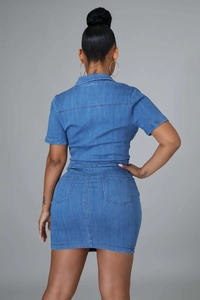 Back view of a slim fit blue denim mini dress featuring short sleeves and rear pockets