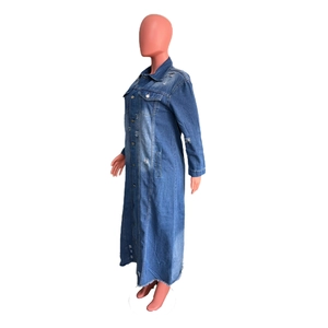 Close-up of distressed denim trench coat showing ripped details and raw hem edges