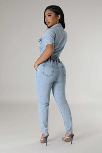 Detail of light blue denim jumpsuit with elastic waist and textured fabric close-up