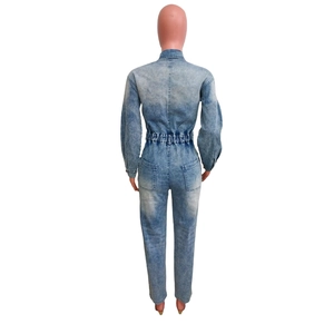 Detail view of light blue denim jumpsuit back with elastic waist and dual pockets