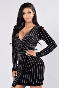 Détail d'une mini-robe en velours noir avec strass argentés verticaux et décolleté en V profond