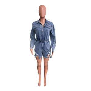 Detail of ripped raw hem and frayed tassels on distressed denim short romper