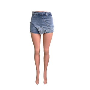 Detail of blue washed denim skort with asymmetrical wrap design and frayed hemline