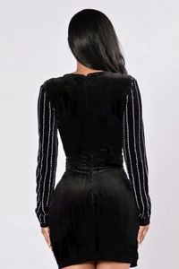 Détail d'une robe moulante en velours noir avec manches longues et ornements en strass