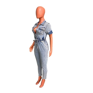 Detail of light blue denim jumpsuit with short sleeves, zipper closure and front pockets