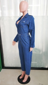 Detail of dark blue denim jumpsuit featuring lapel collar, button waist, and chest pocket