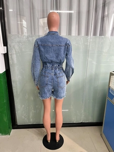 Back view of light blue denim romper featuring elastic waist and frayed hem details