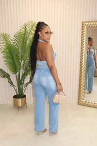 Detail of light blue denim jumpsuit featuring backless halter neck and side cargo pockets
