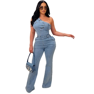 Dettaglio tuta in denim lavato blu con taglio monospalla e borsa a mano logata