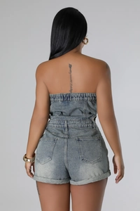 Rear view of denim strapless romper showing back pockets and rolled cuffs on blue fabric