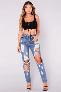 Detail of high-waisted distressed blue denim jeans with ripped knees and frayed edges