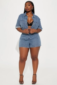 Detailed close-up of blue washed denim playsuit with chest pockets and metal buttons