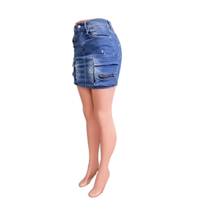 Détail de mini-jupe en jean bleu délavé avec poche cargo et taches de peinture blanche