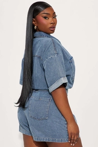 Side back view of short sleeve washed blue denim romper with rear pockets and classic collar