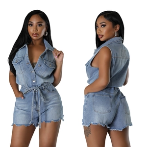 Détail d'un combishort en jean bleu avec boutons, poches poitrine et ourlet effiloché