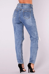 Detail of high-waisted blue ripped jeans showing back pockets and distressed denim texture