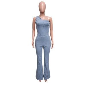 Dettaglio tuta in denim celeste con taglio monospalla e gamba a zampa slim fit