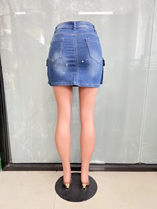 Détail de mini-jupe en jean bleu clair avec taches de peinture et poches cargo