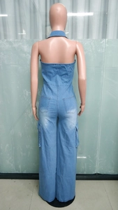 Detail of light blue wash denim jumpsuit showing back view with halter neck and cargo pockets