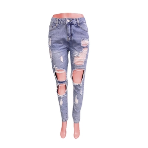 Detailed view of light blue slim fit ripped jeans with distressed knee holes and buttons