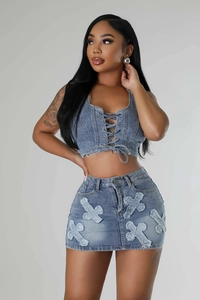Detail of cross embroidery and distressed edges on blue denim two-piece skirt set