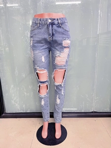 Detailed view of light blue distressed skinny jeans with heavy knee rips and whiskers