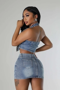 Detail view of denim two-piece set featuring halter top and fitted skirt with back pockets