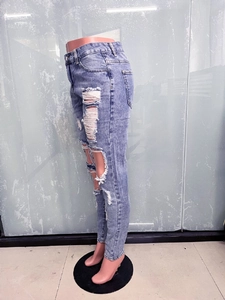 Detailed view of light blue distressed denim jeans with ripped holes and frayed textures