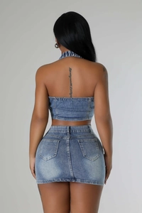 Detail view of denim two-piece set featuring backless halter top and cross embroidery