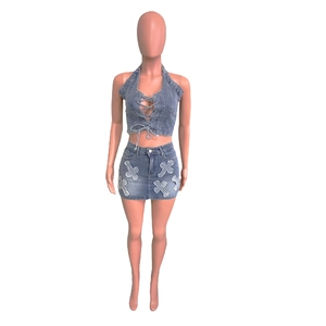 Detail of blue denim two-piece set with halter crop top and cross patches on skirt