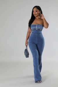 Detailed view of cutout waist design and metal buckle on blue denim jumpsuit