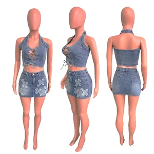 Detail of light blue washed denim set with lace-up halter top and cross patches on skirt