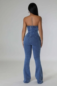 Detail of denim jumpsuit back with adjustable straps and metallic zipper closure