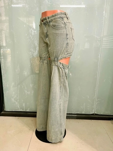 Détail d'un jean délavé clair avec un design créatif à boucle ajourée sur la cuisse